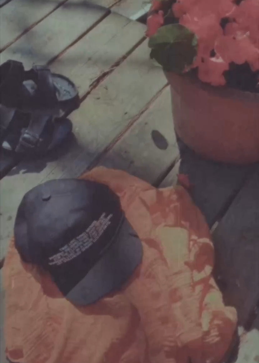 Orange outfit and a black cap on a wooden dock with potted plants and birkenstock sandals