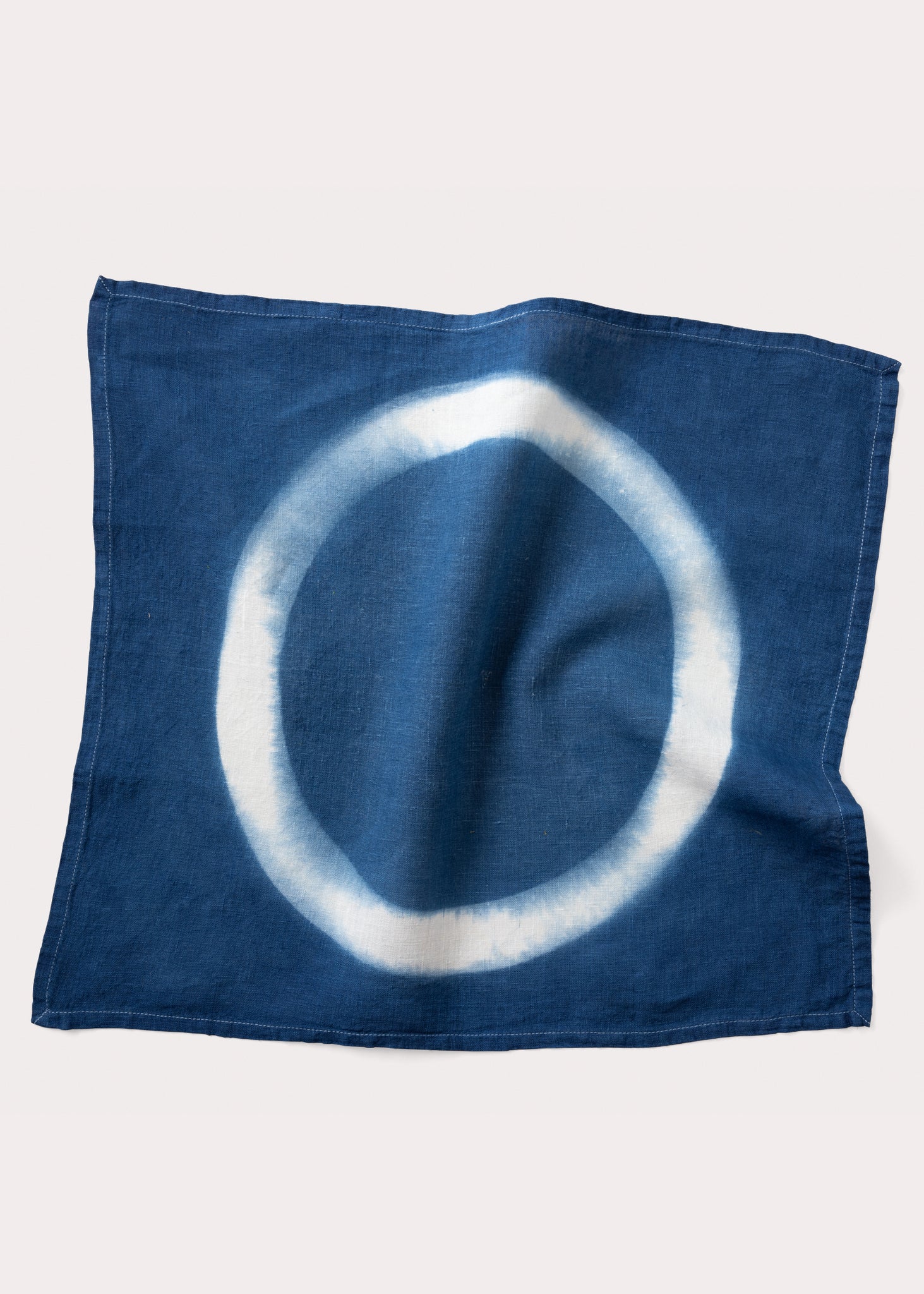 A square-shaped indigo altar cloth with a white circle in the center, displayed on a plain background.