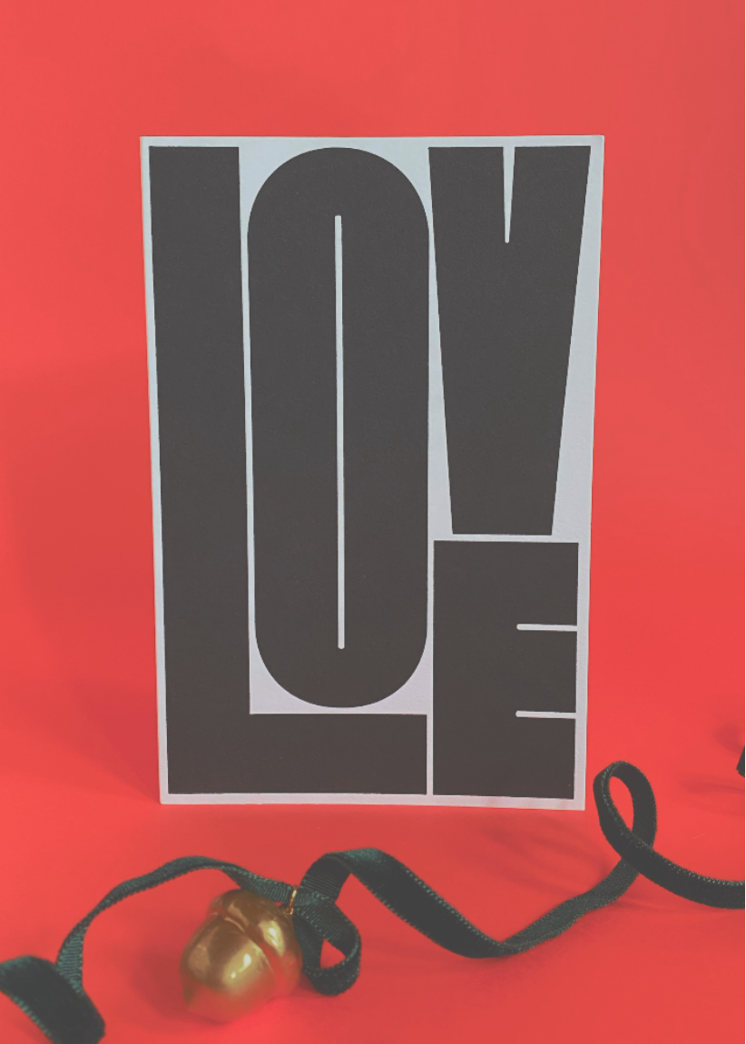 Big Love greeting Card with 'LOVE' printed on it against a red background with velvet Christmas ribbon and gold ornament
