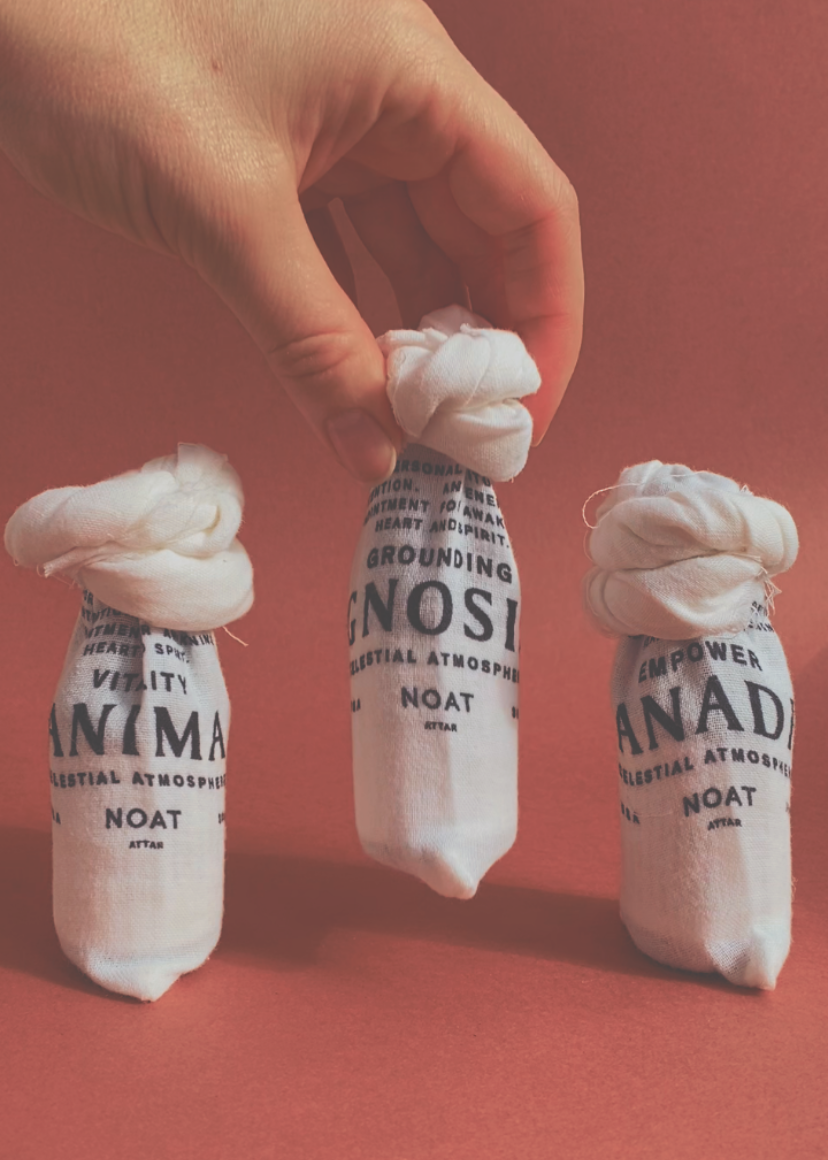Noat_Celestial_Atmosphere_Gnosis_with_cedarwods_sandalwood_bergamot_clove_packaged with anadi and anima held by hand on a deep red background